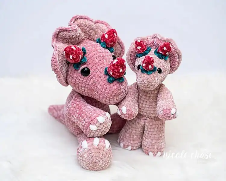 Whimsical crochet Strawberry Tanner the Triceratops, a modified design featuring red body and green frill to resemble a strawberry.