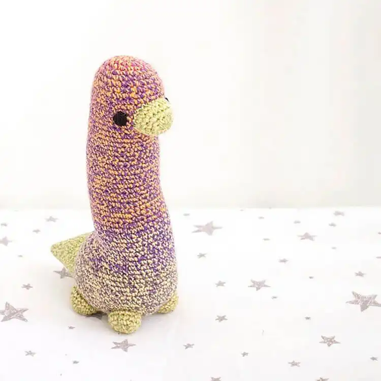 Adorable green crochet Brontosaurus Dinosaur Amigurumi, approximately 9.5 inches tall, with friendly eyes and a classic shape.
