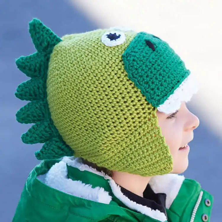 Cozy green crochet Caron Hatosaurus, a child's hat designed with dinosaur spikes on top, perfect for warmth and fun.