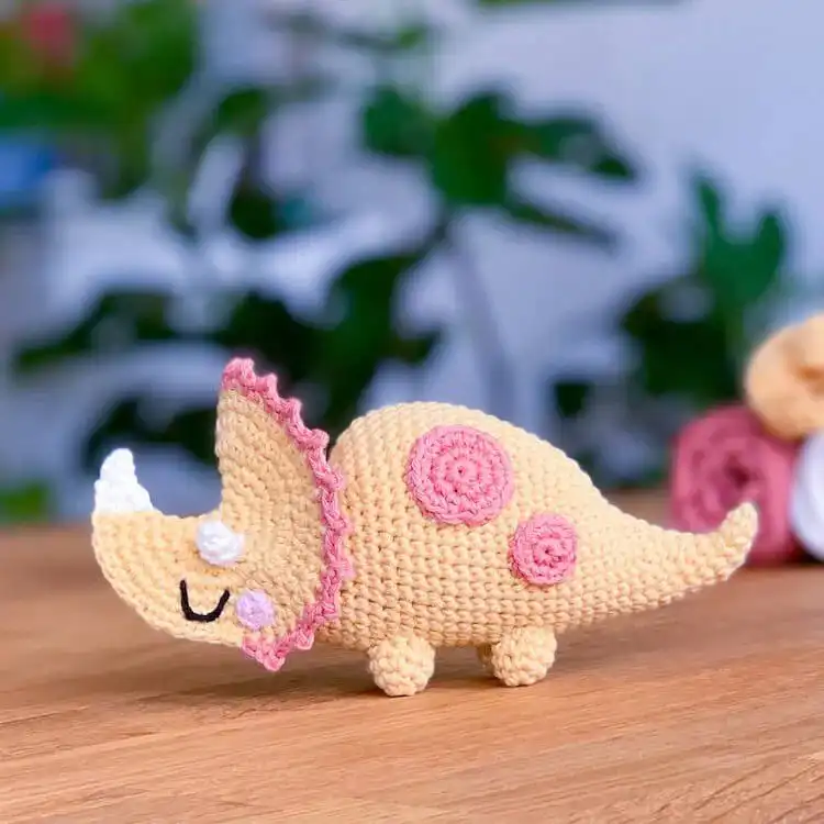 Charming crochet Triceratops dinosaur with its signature frill and three horns, rendered in a soft blue yarn, ready for play or display.