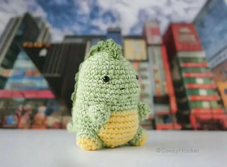 Chubby crochet Chubzilla, an adorable, less-threatening version of Godzilla, with a stout body and dorsal plates in a grey color.