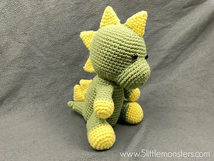 Soft green crochet dinosaur softie standing approximately 9 inches tall, with simple features and a friendly expression, ideal for cuddles.