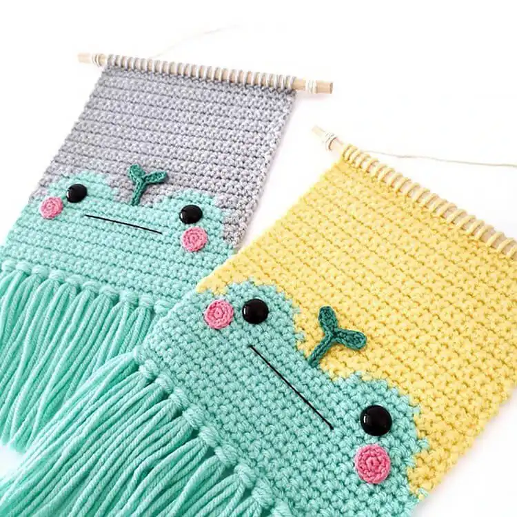 Round crochet Frog Wall Hanging in green and white, depicting a cheerful frog face