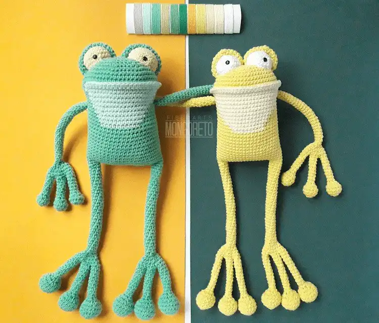Two slender crochet frogs with very long, poseable legs, sitting side by side