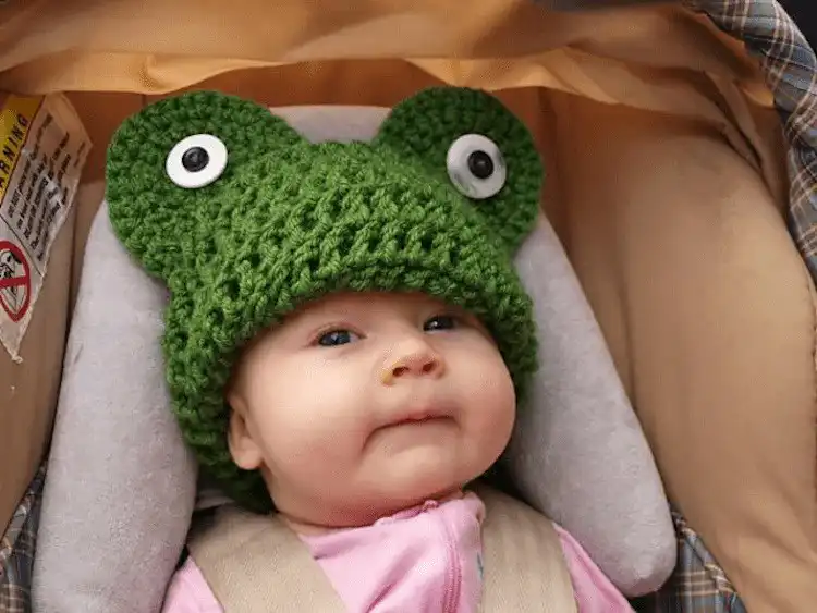 Close-up of a green crochet Frog Head Hat for babies, featuring big eyes and rosy cheeks
