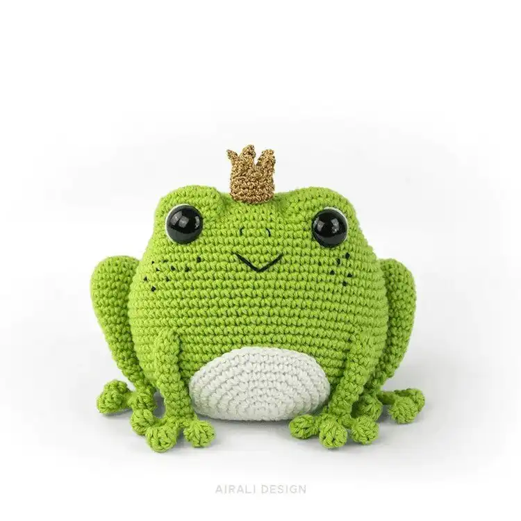 Charming crochet Prince Perry the Frog amigurumi wearing a golden crown, with freckles and rosy cheeks
