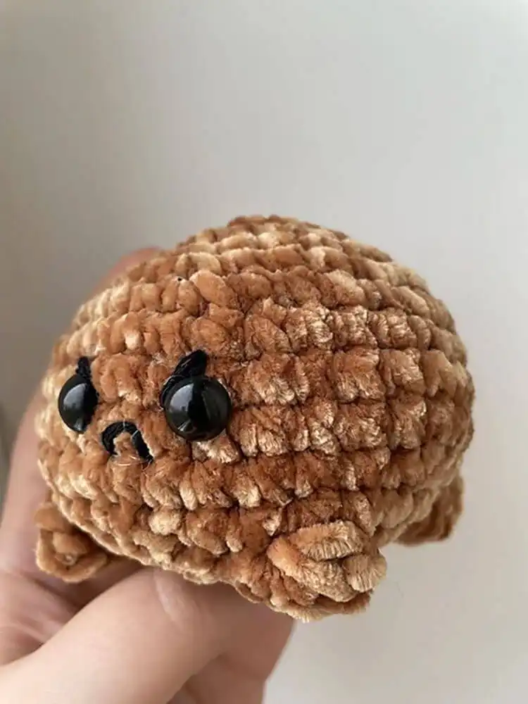 Tiny, textured crochet Desert Rain Frog amigurumi in light brown yarn, showcasing its unique shape