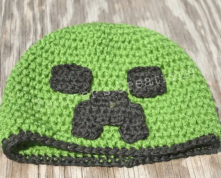 Child wearing a green crocheted Minecraft Creeper hat