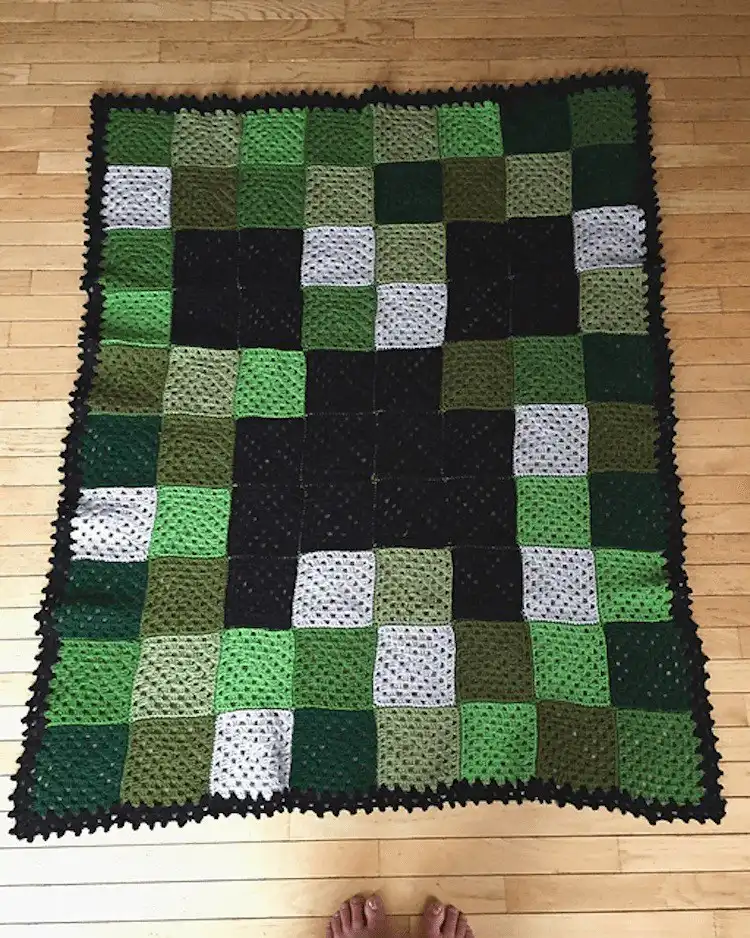 Green and black crocheted blanket with a large Minecraft Creeper face design