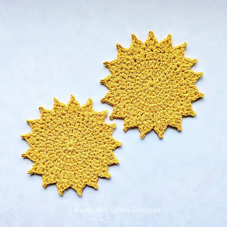 A cheerful yellow crochet sun coaster with radiating stitches, perfect for summer home decor.