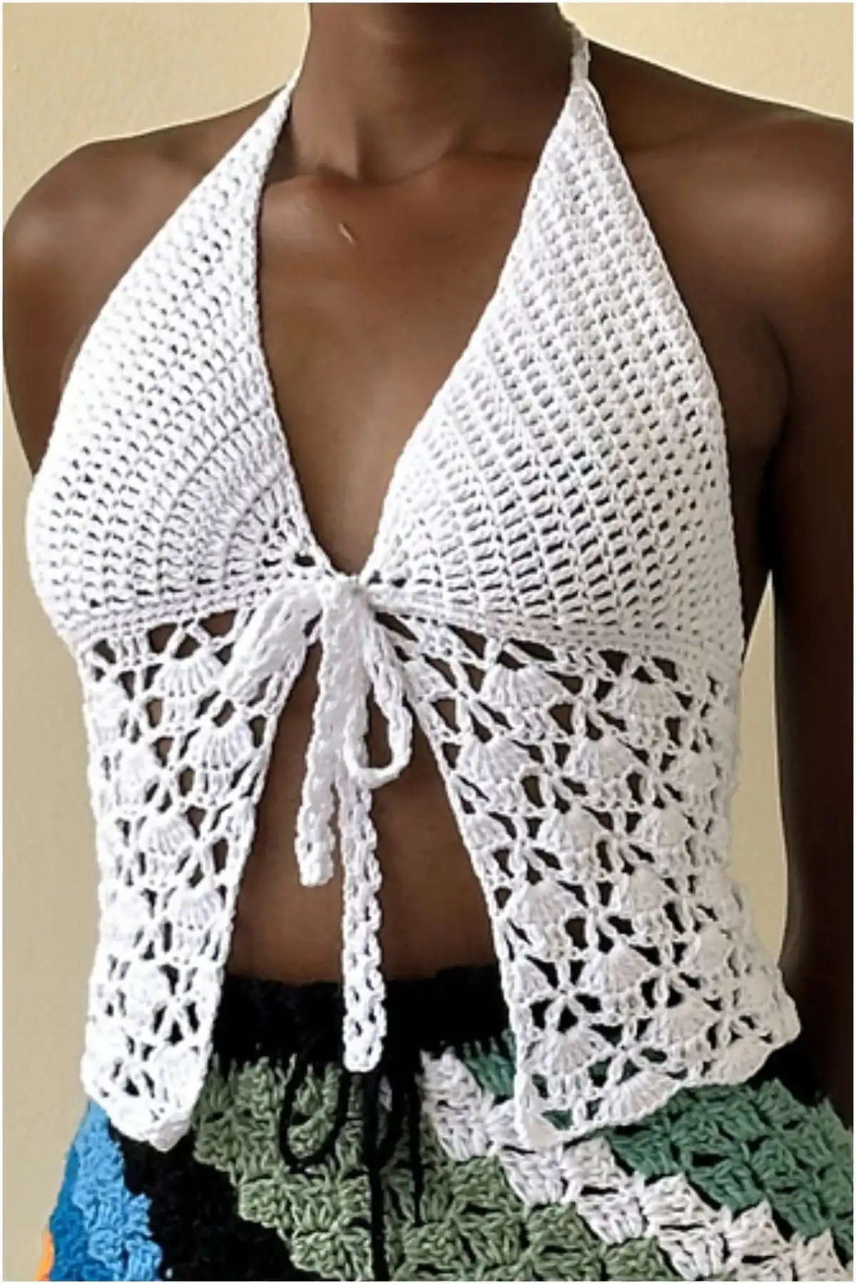 Woman wearing a white front-tie crocheted butterfly top by Sheila Mutaawe, featuring a classic, elegant design with lace details.
