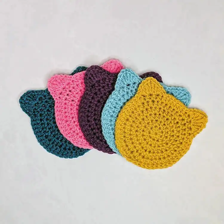 Collection of various colored Crochet Cat Coasters, highlighting different yarn choices and the consistent design of the free easy pattern.