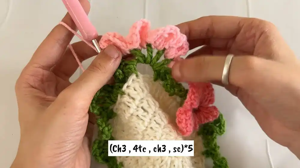 Process of adding green leaf loops to the crocheted coaster base, forming the foundation for the flower petals.