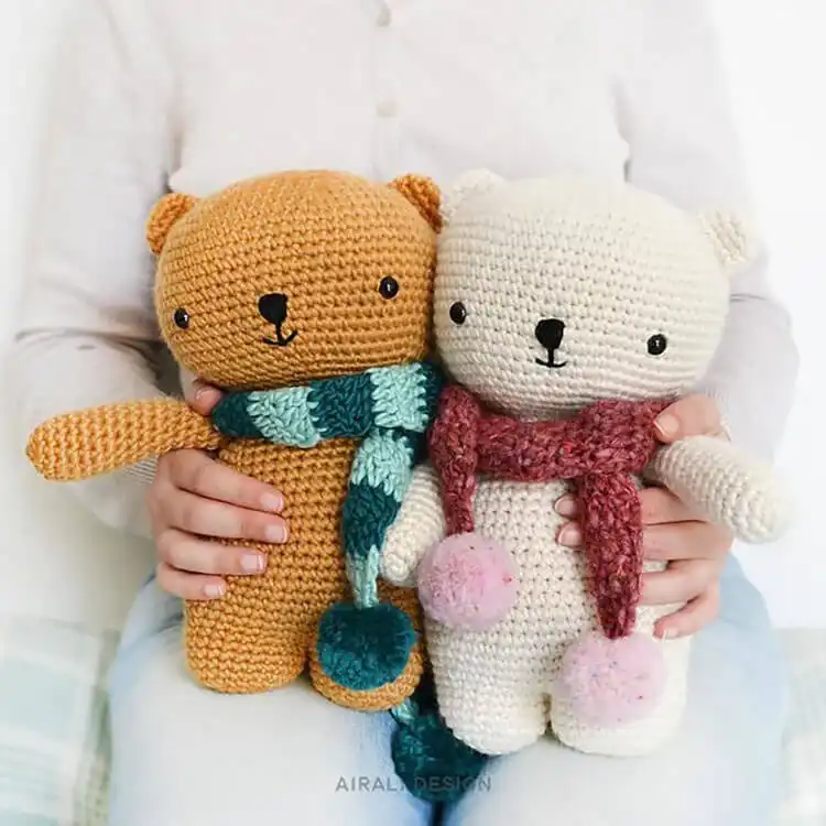 Crochet teddy bear wearing a miniature red and white striped scarf.