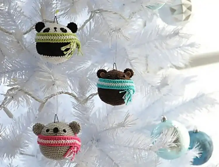 Three small amigurumi teddy ornaments: a brown bear, a panda, and a koala.