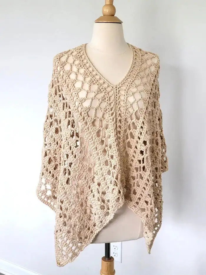 Cream-colored Crochet Lacy Summer Poncho laid flat, highlighting the airy stitch pattern and lightweight cotton yarn ideal for midsummer.