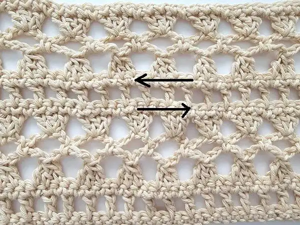 Close-up of a tapestry needle weaving in yarn ends along single crochet rows of the finished Crochet Lacy Summer Poncho.