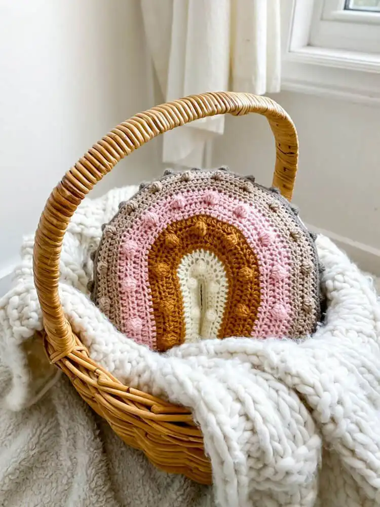 Bright and colorful crochet rainbow pillow with distinct striped arches