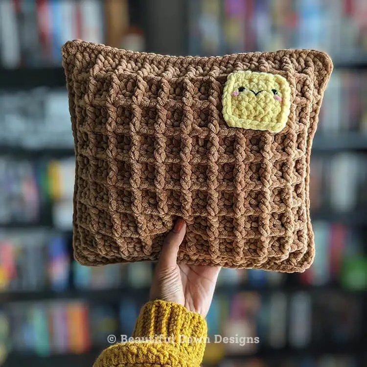 Close-up of a square crochet waffle pillow in a mustard yellow color, showcasing its deep texture