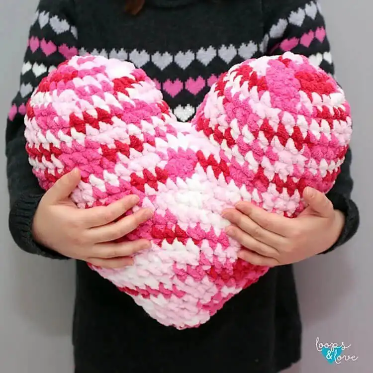 Plush red crochet heart pillow resting on a sofa