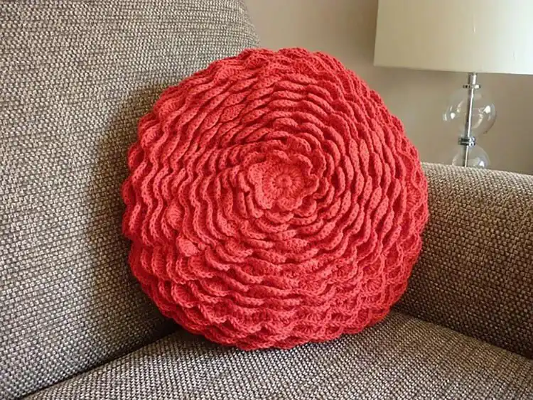 Round crochet cushion designed as a blooming flower with colorful petals and a yellow center