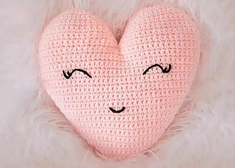 Soft pink crochet heart-shaped pillow on a neutral background