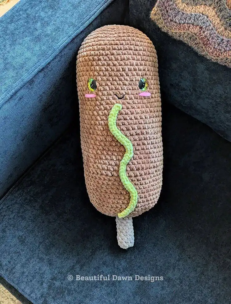 Humorous jumbo crochet corn dog plushie with a stick detail