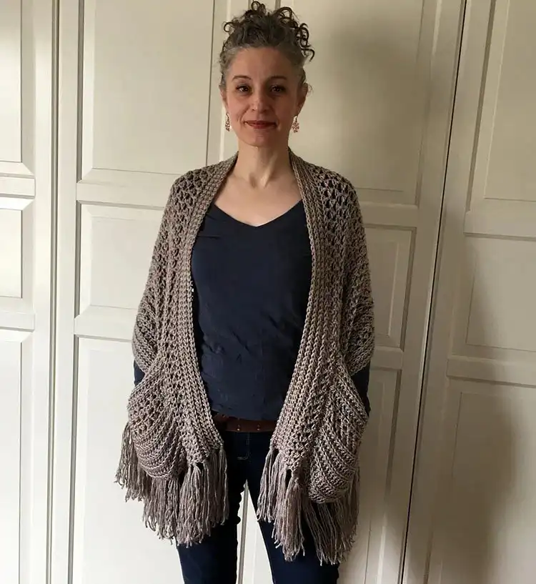 A beautiful Boho Crochet Shawl with Fringe, made in a warm autumnal color, draped for a stylish look.