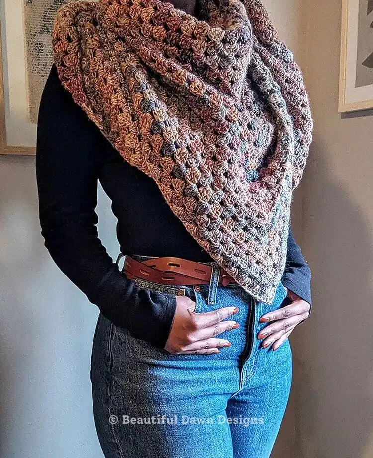 A colorful Granny Shawl draped over a chair, showcasing its iconic motif and varied yarn colors.