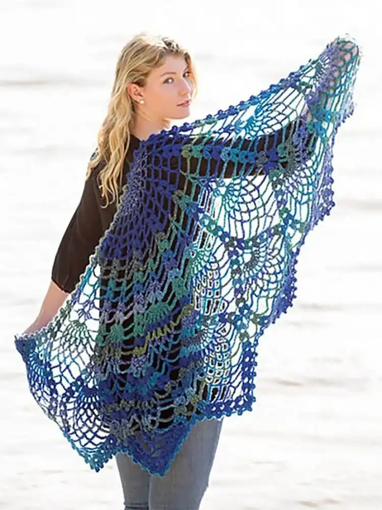 An intricate Pineapple Peacock Shawl in a rich jewel tone, highlighting its detailed lace work.