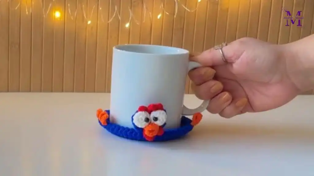 A charming, handmade Cute Crochet Chicken Mug Coaster in white and blue, hugging a coffee mug, showcasing the mug hugger pattern and its potential as an easy gift idea.