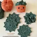 A Gobble Coaster, a crocheted turkey coaster featuring a brown body, yellow beak, red wattle, and vibrant multicolored tail feathers on a white background.