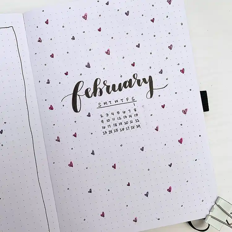 Minimalist bullet journal page with small, scattered heart illustrations and a simple calendar layout.