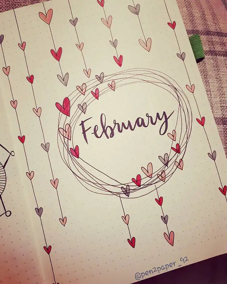 February bullet journal cover page featuring hearts hanging from delicate strings around the month's title.