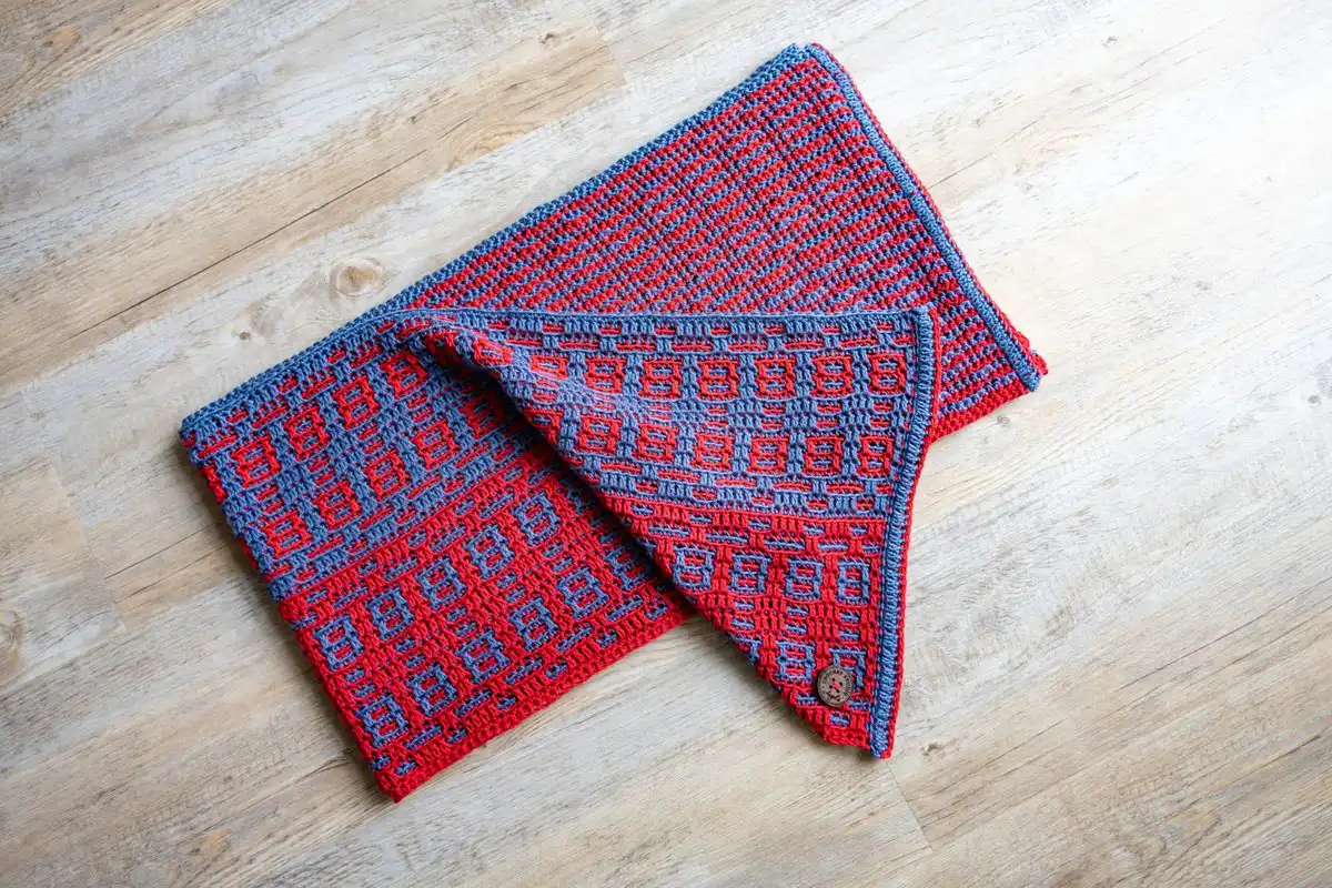 Crochet mosaic scarf in blue and red, folded on a floor, ready for use, from the Fire and Ice Scarf Free Crochet Pattern.