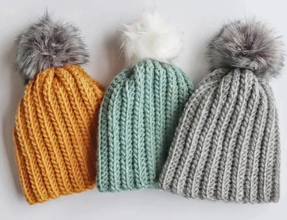A simple grey crocheted beanie on a wooden surface, showcasing the Bottom Up Beanie pattern from Free Crochet Hat Patterns for Babies and Kids.