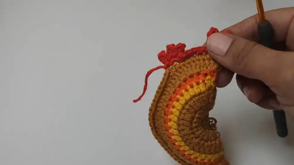 Detailed image showing the creation of the red comb for the Free Crochet Rooster Keychain Pattern using puff stitches.