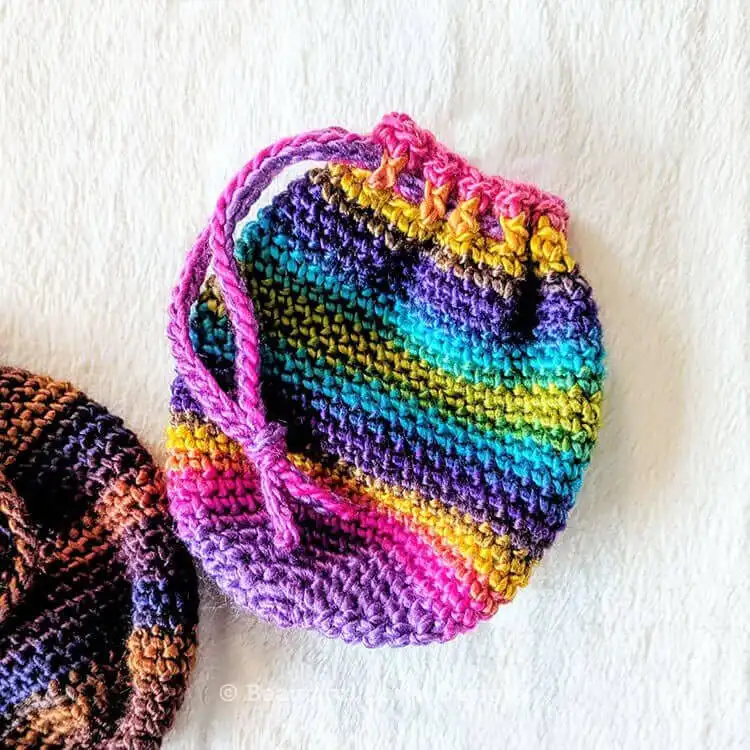 A set of colorful crochet pouches in pink, yellow, and blue, perfect for storing small items.