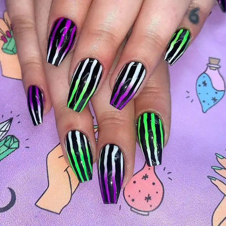 Unique Glow in the Dark Beetlejuice gradient nails with striped bases and a subtle green or purple fade.