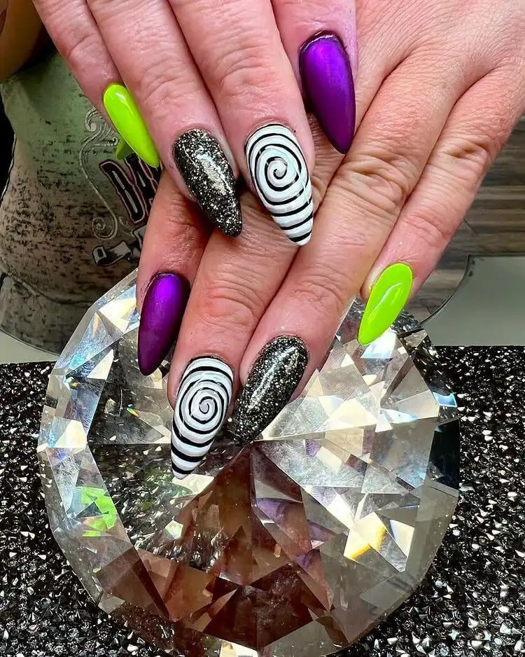 Glamorous Glow in the Dark Beetlejuice Nails with black base and shimmering glitter accents on stiletto shapes.