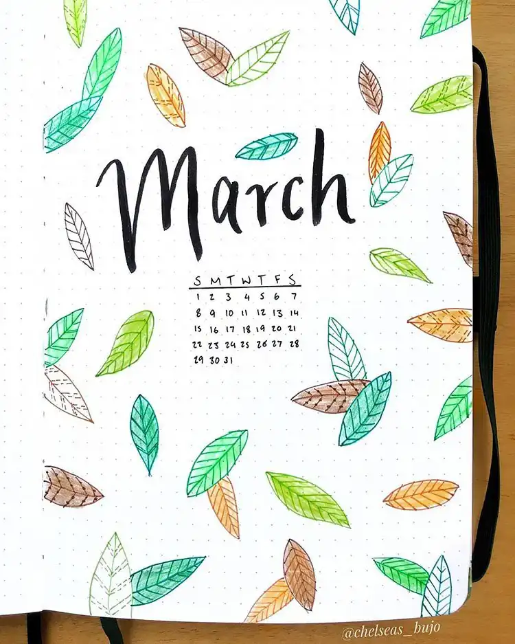 March bullet journal cover page featuring an array of green, brown, and orange autumn leaves gracefully falling.