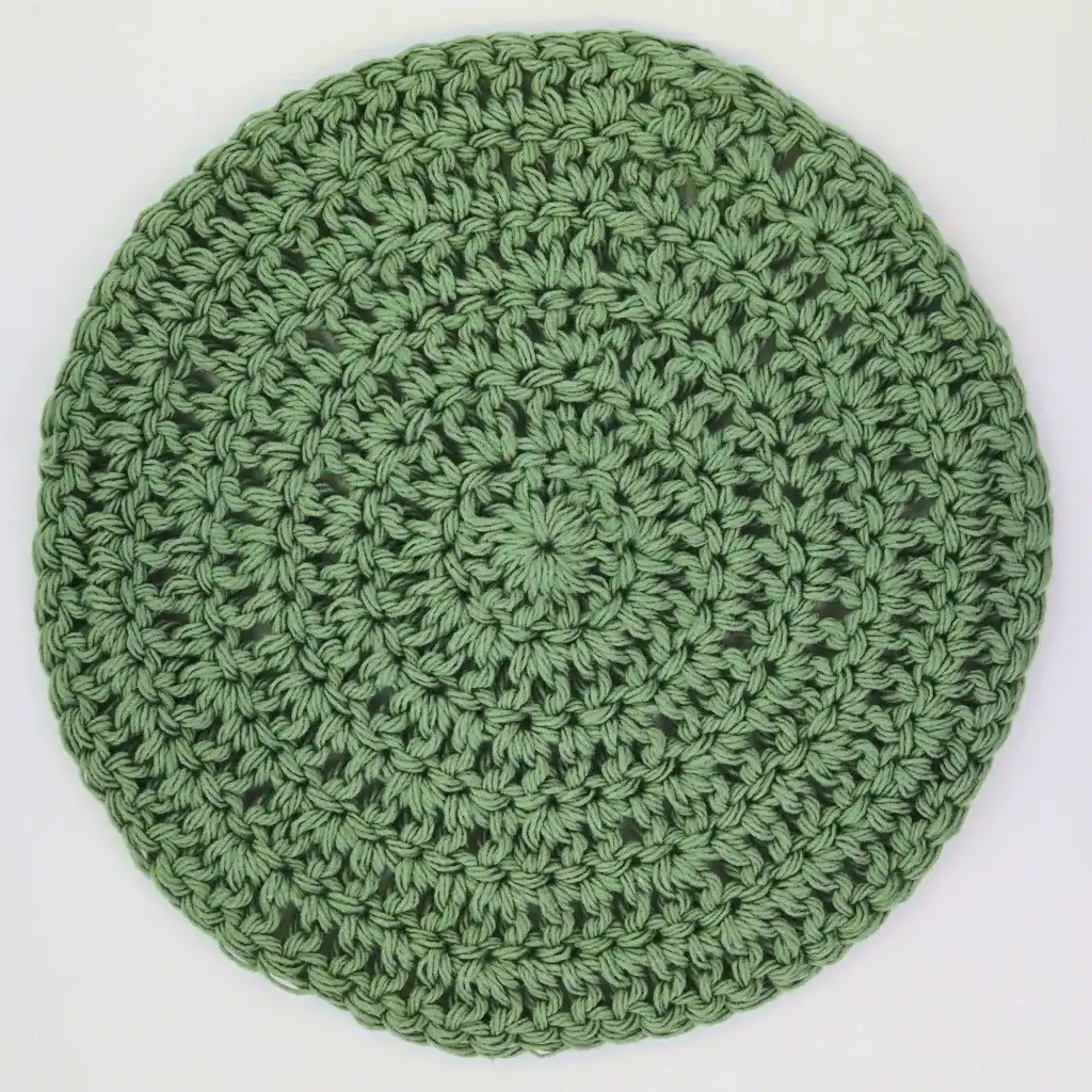 A finished, large double crochet circle, demonstrating the smooth, flat texture and consistent stitch work achieved with proper increases.