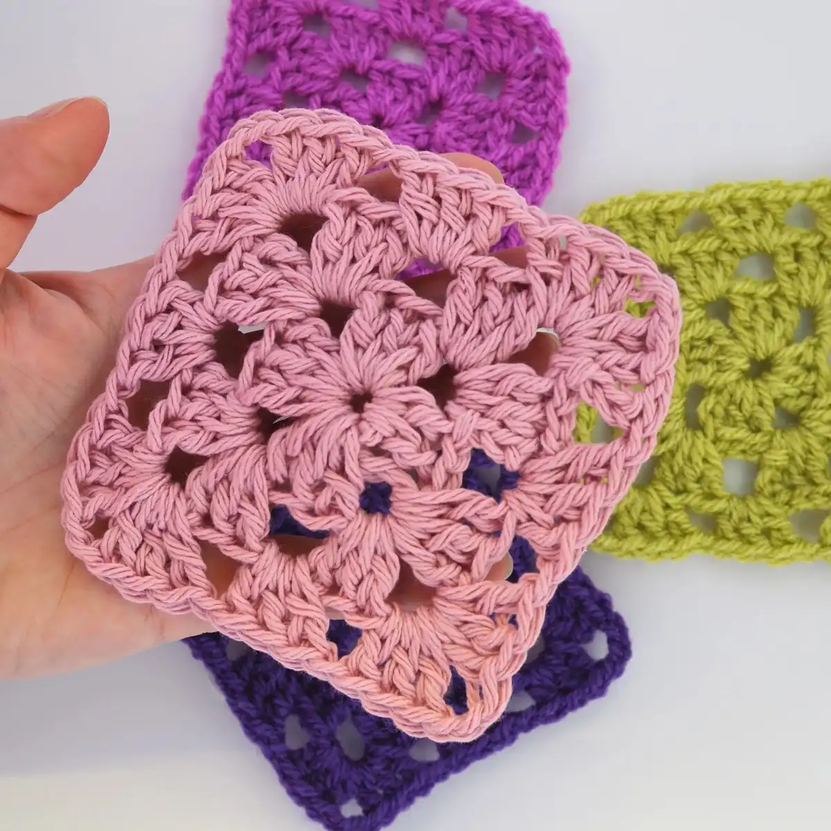 A solid granny square crocheted in pink yarn, demonstrating the dense and uniform texture, a staple for many crochet projects.