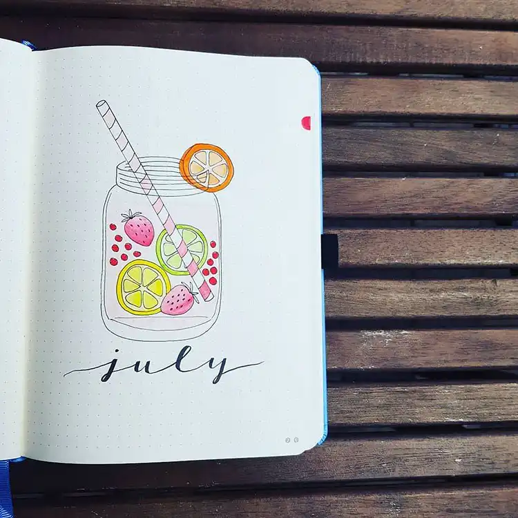 July Bullet Journal Cover Page Ideas 2 Bullet journal cover page with a mason jar filled with pink lemonade and various fruits for July.
