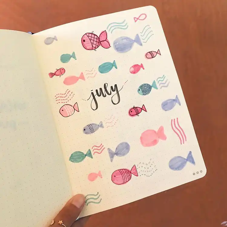 July Bullet Journal Cover Page Ideas 10 Colorful fish doodles on a simple July bullet journal cover page.
