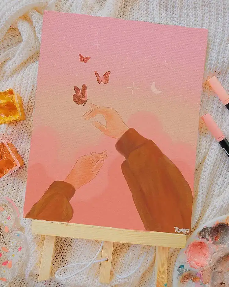 A hand holding a painting with a butterfly and flowers rendered in gouache, demonstrating the medium's delicate possibilities, helpful for learning how to paint a gouache flower.