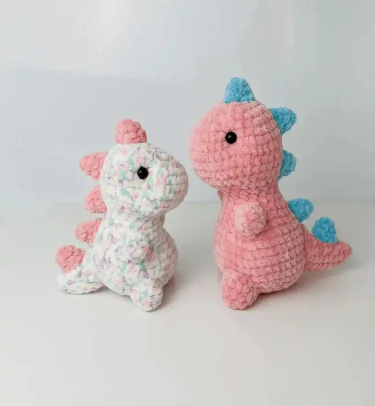A pair of charming crochet Rose and Lily amigurumi dinosaurs, in soft pastel colors, showcasing their unique playful designs.
