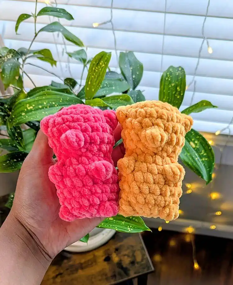 A collection of colorful, squishy no-sew crochet gummy bears, glowing with internal lights, showcasing the soft chenille yarn texture.