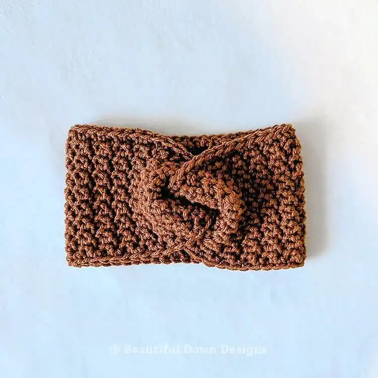 A cozy chestnut-colored crochet ear warmer, showcasing its thick, snug texture made with bulky yarn, perfect for cold weather.