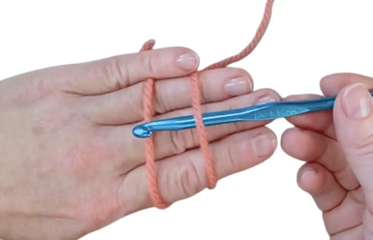 Step 2: Securing yarn tail with thumb and wrapping around fingers for magic ring.